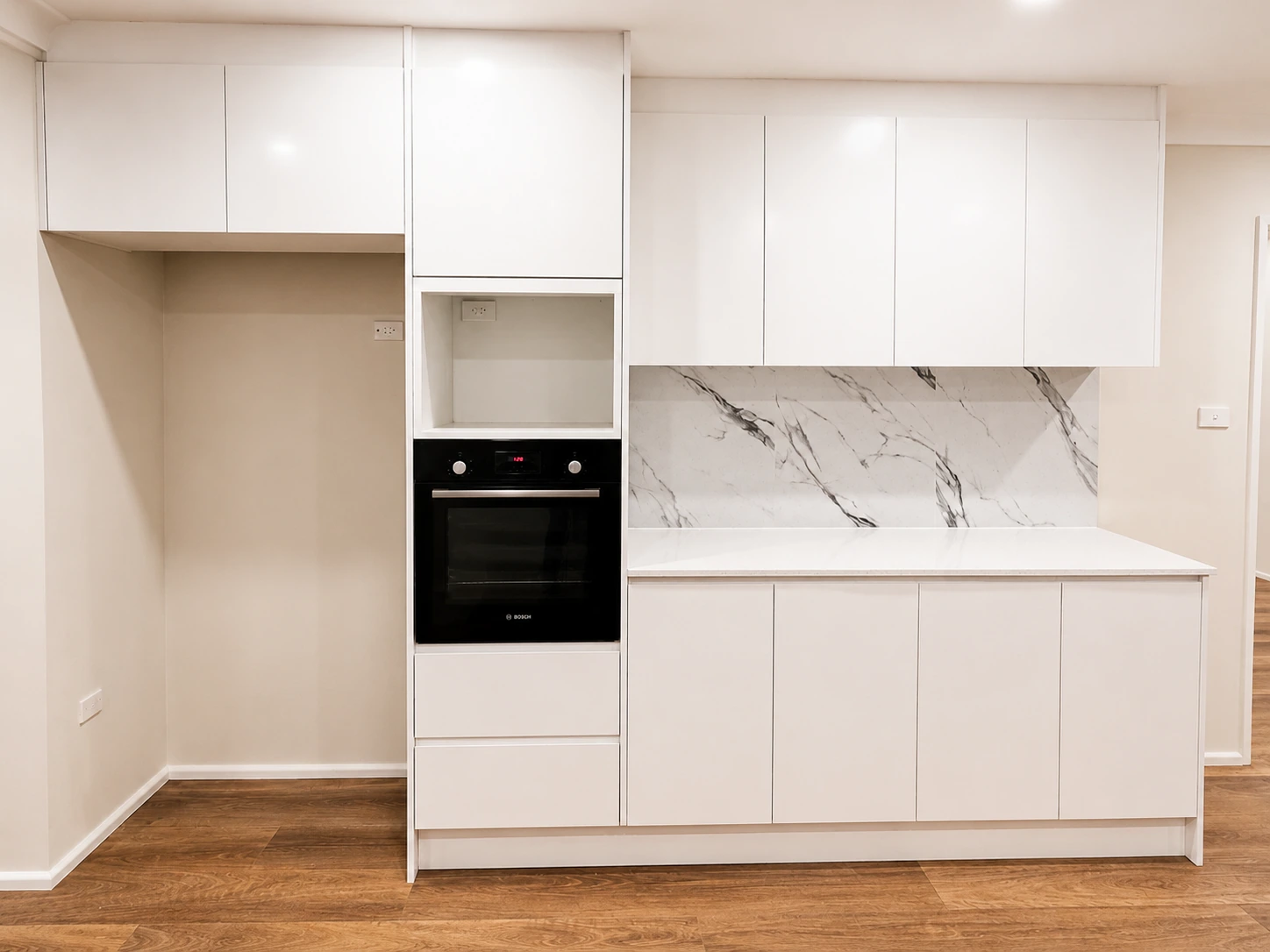 Castle Hill kitchen joinery — white cabinetry with a built-in black oven and marble-look splashback