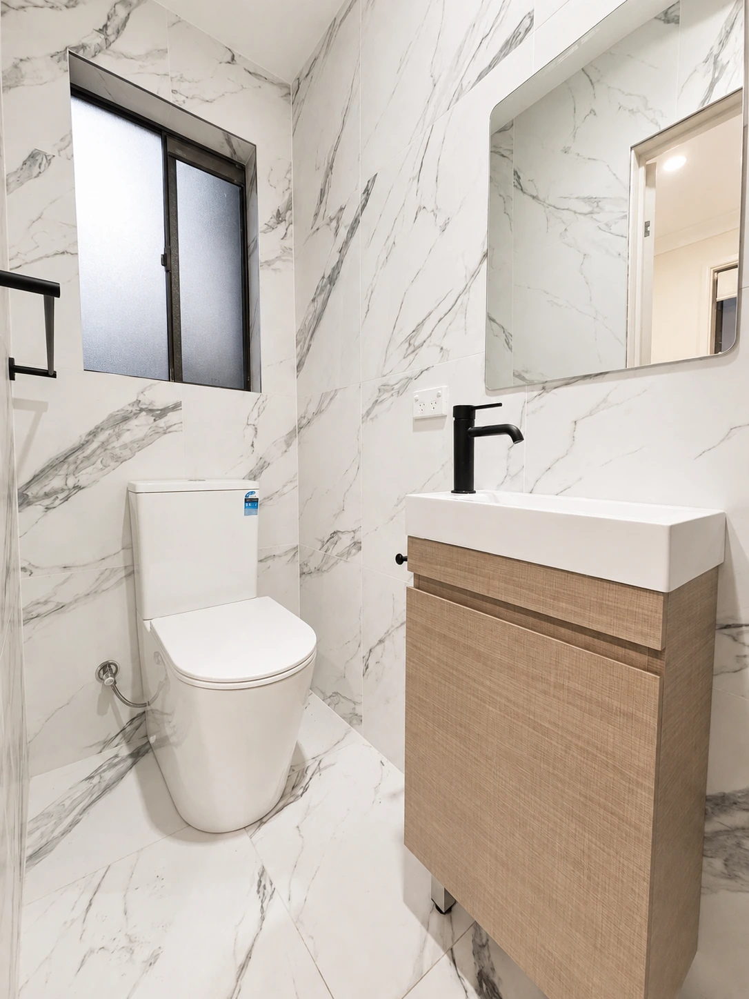 Castle Hill powder room — marble-look tiling with a timber wall-hung vanity