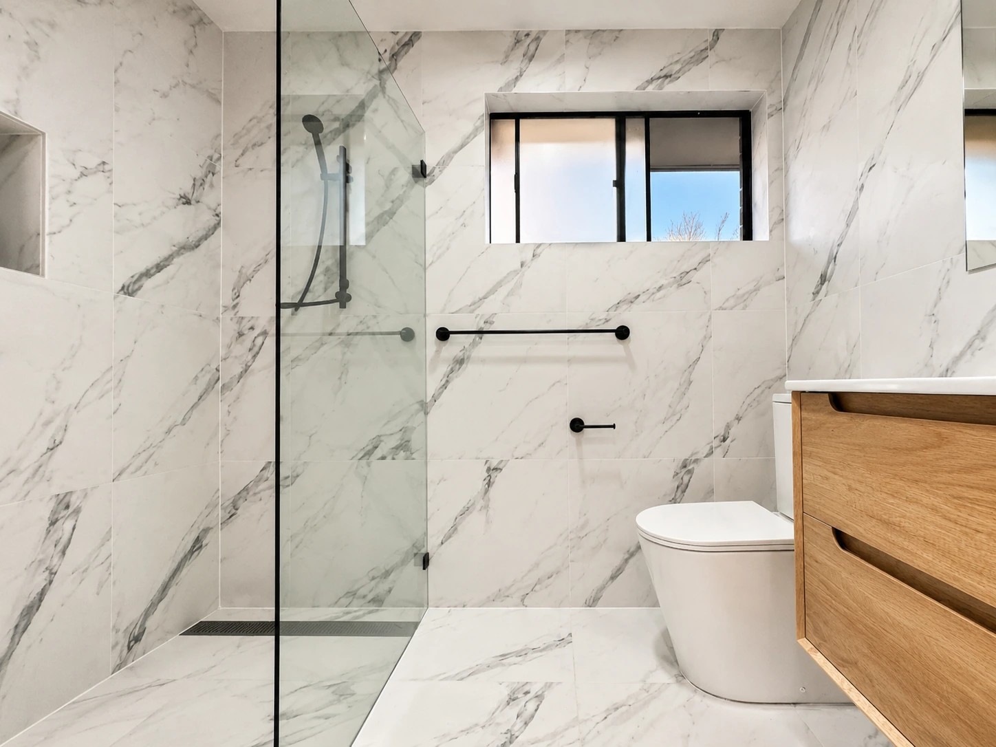 Castle Hill bathroom — frameless walk-in shower and timber vanity in marble-look tiling