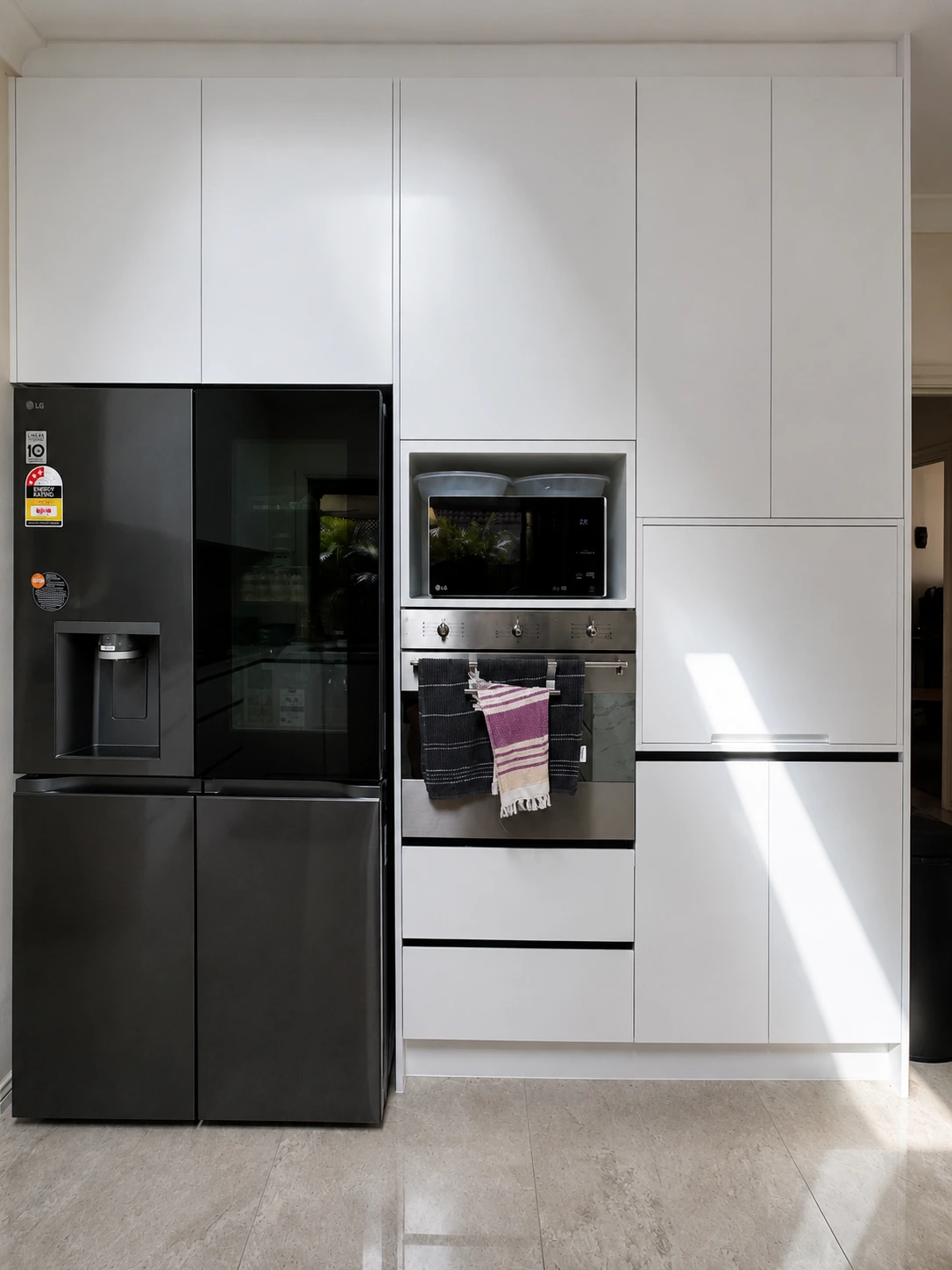 Castle Hill kitchen — full-height white handleless cabinetry with an integrated black fridge and built-in oven