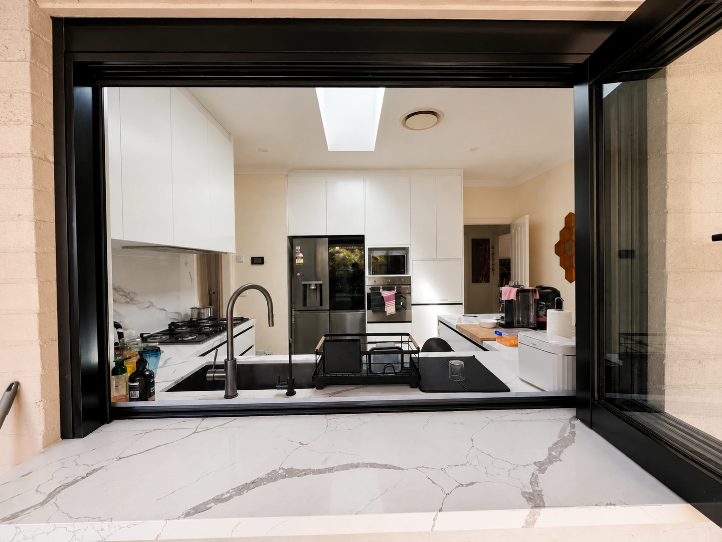 Castle Hill kitchen viewed from the alfresco through the black bi-fold servery window