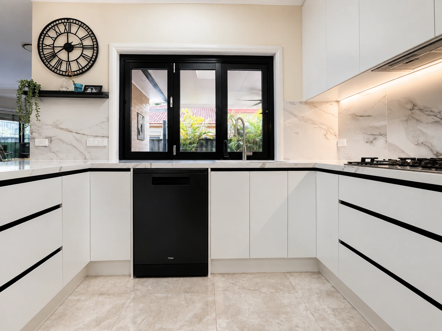 Castle Hill kitchen — marble-look splashback and benchtop, black dishwasher and gas cooktop with a servery to the courtyard