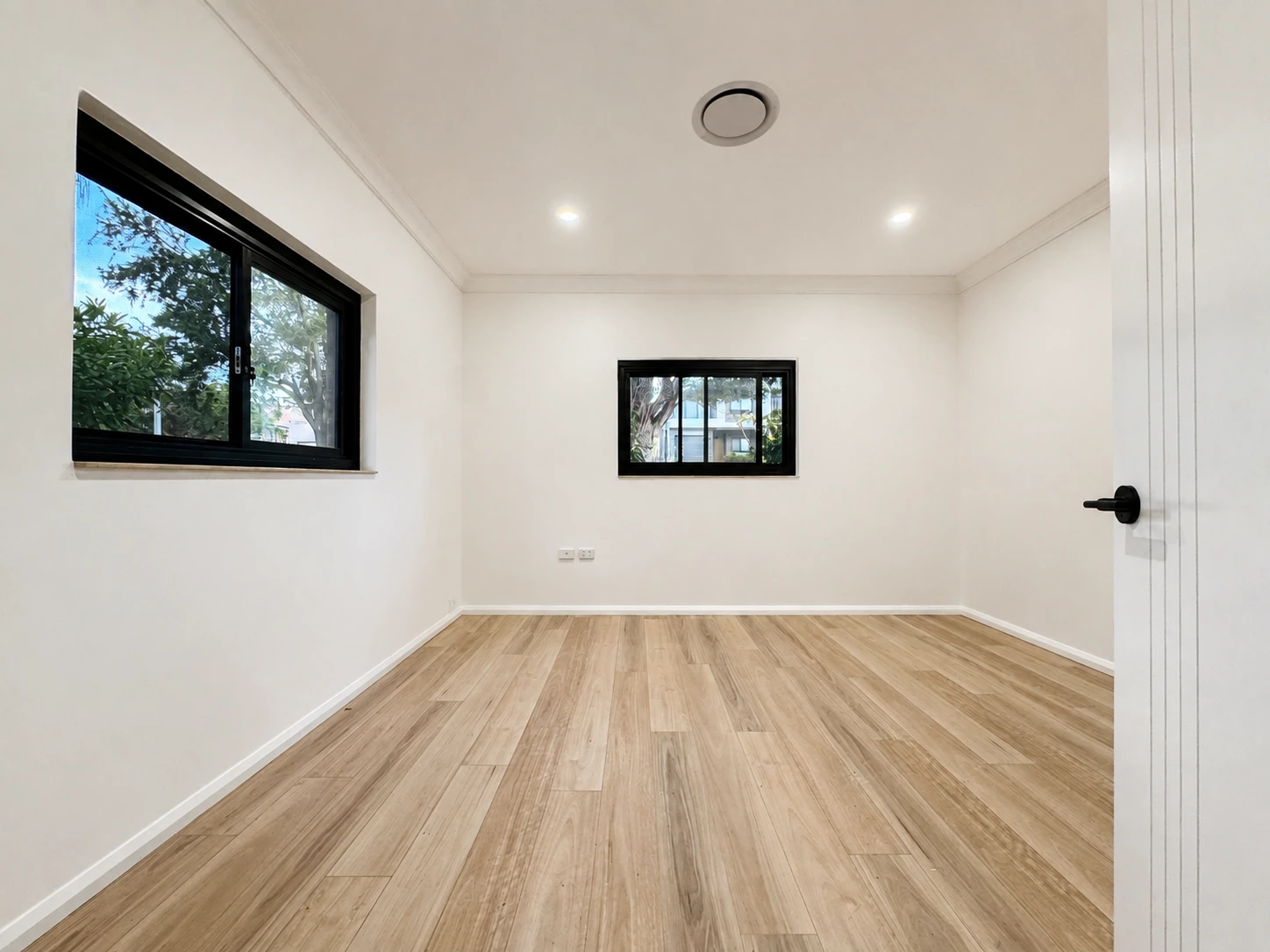 Renovated Strathfield bedroom with two black-framed windows, new cornices and timber flooring