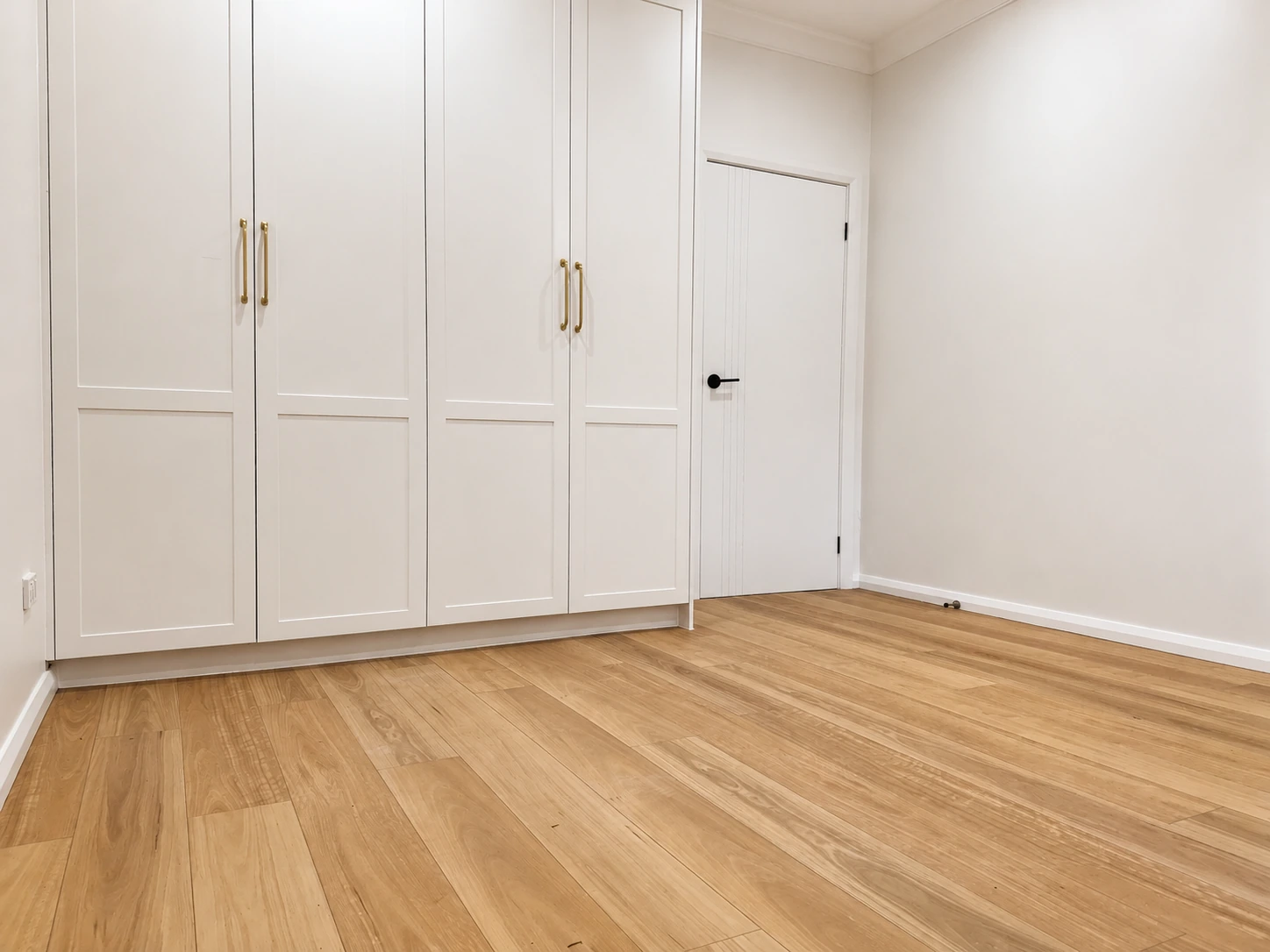 Second Strathfield bedroom — floor-to-ceiling shaker wardrobes with brass handles beside a new door with black hardware