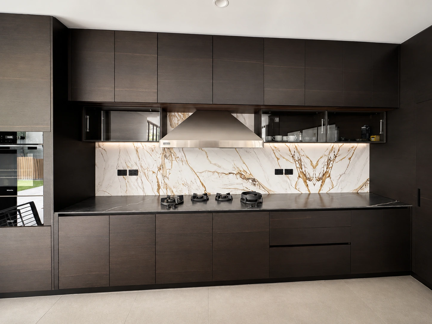 Dark timber kitchen in North Ryde — book-matched Calacatta-gold marble splashback and black stone benchtop