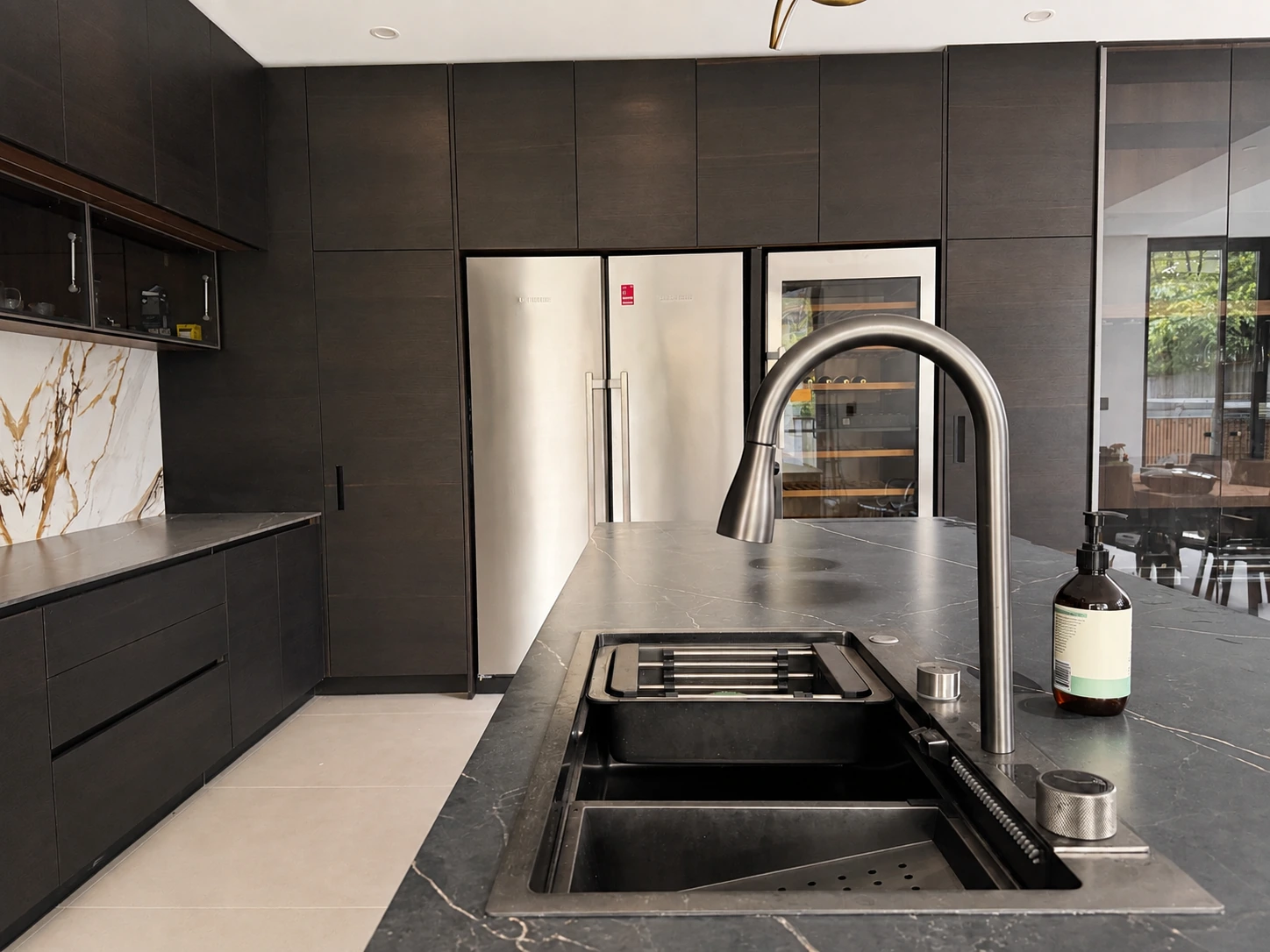 North Ryde kitchen island — black stone benchtop with undermount sink, dark timber cabinetry and an integrated wine cabinet
