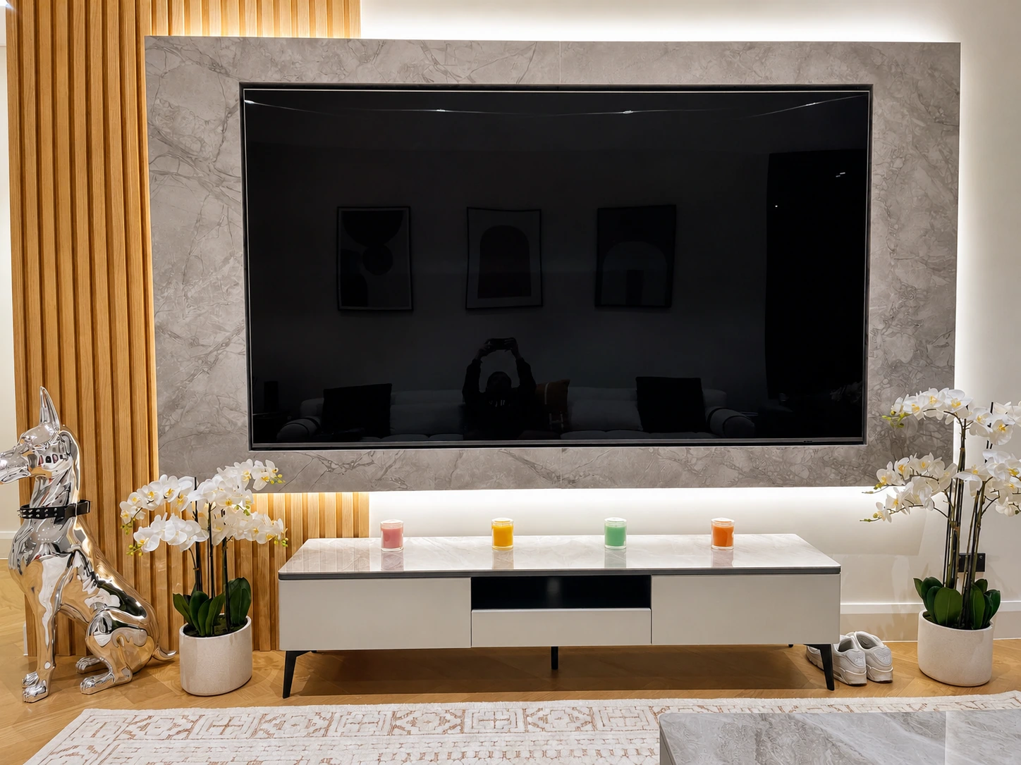 Rhodes apartment television wall close up — grey stone panel with concealed LED recesses above and below, fluted oak battens down its left edge, over a stone-top console