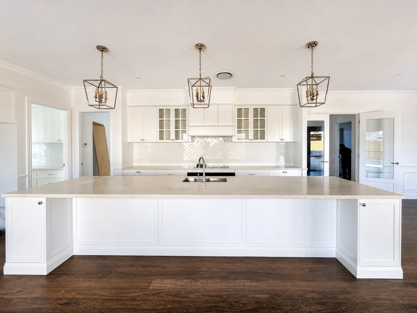 Hamptons kitchen renovation in Willoughby — stone island bench, shaker joinery and lantern pendants over dark timber floors