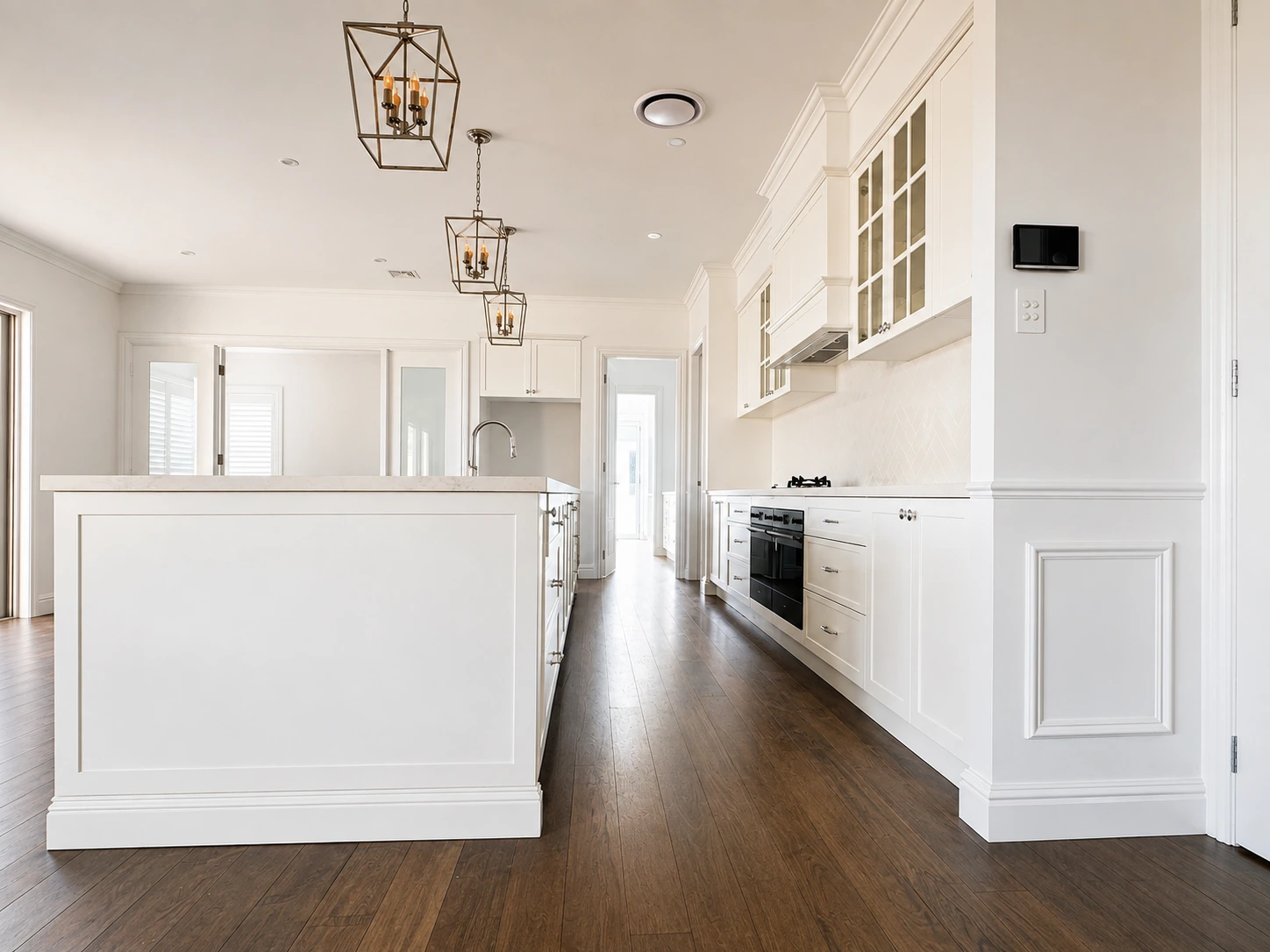 Willoughby Hamptons kitchen — white shaker cabinetry, a black oven and herringbone splashback on dark timber floors