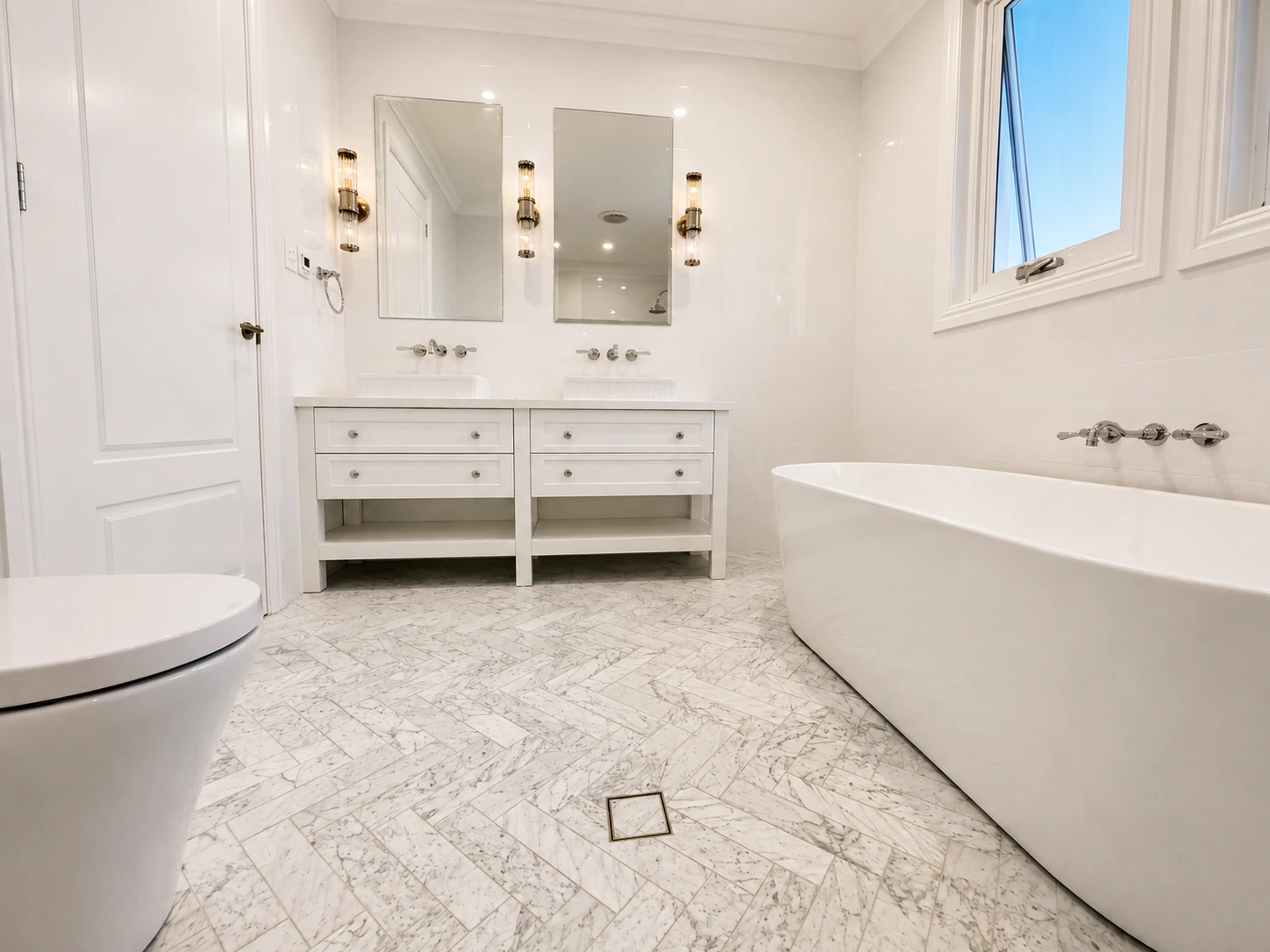 Willoughby bathroom — freestanding bath and double vanity over marble herringbone flooring